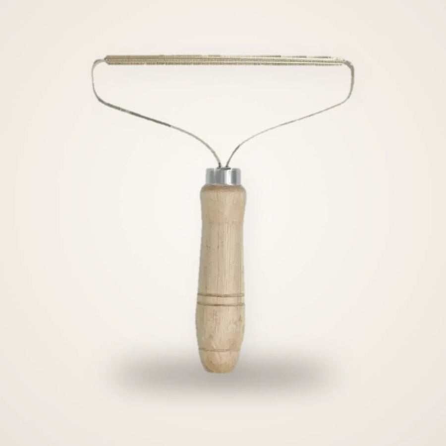 Brosse anti-poils chat en bois et cuivre sur fond neutre